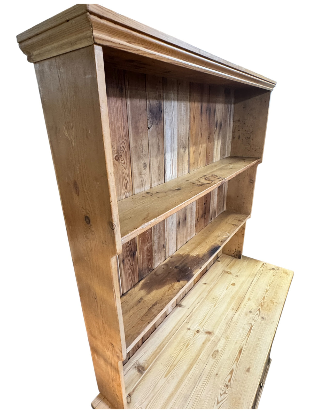 Side angled view of an antique pine kitchen dresser showing shelf depth, pine worktop and boarded back construction.