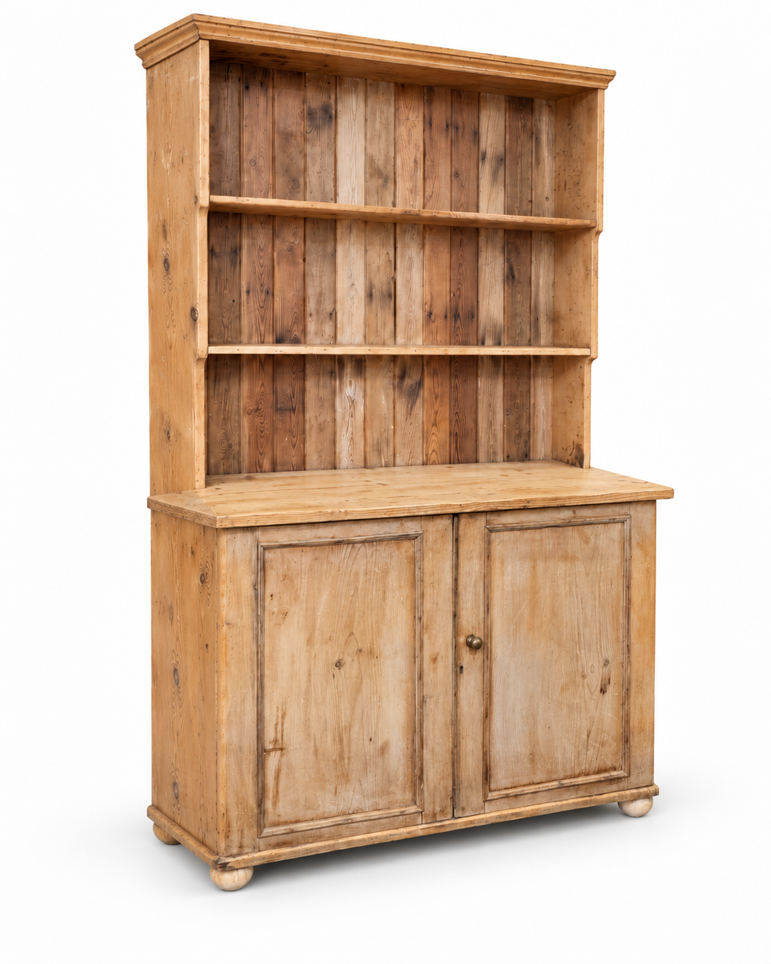 Three quarter studio view of an antique pine kitchen dresser on a white background showing side depth, open shelves and cupboard base.