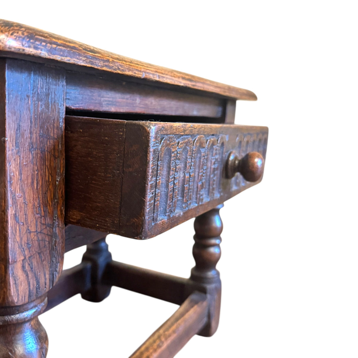 Close-up of carved oak drawer front with arcaded decoration, turned wooden knob and aged surface wear