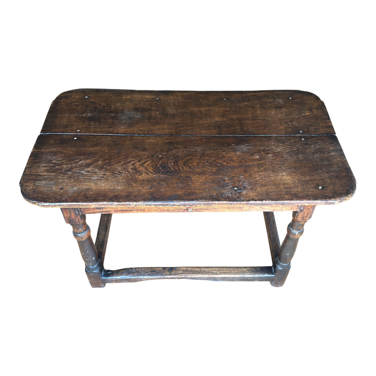 Three-quarter view of the antique oak tavern table showing its two-board top, rounded corners, turned legs and rich dark patina.