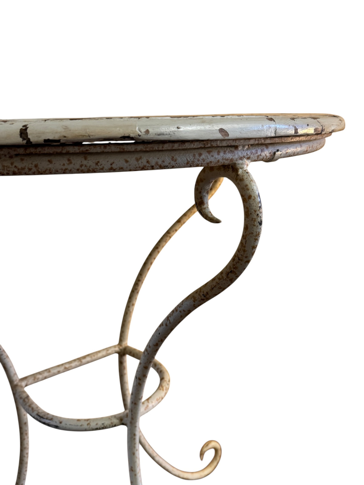 Close-up of vintage wrought iron console table frame showing worn cream paint, oxidation and decorative scroll detail.
