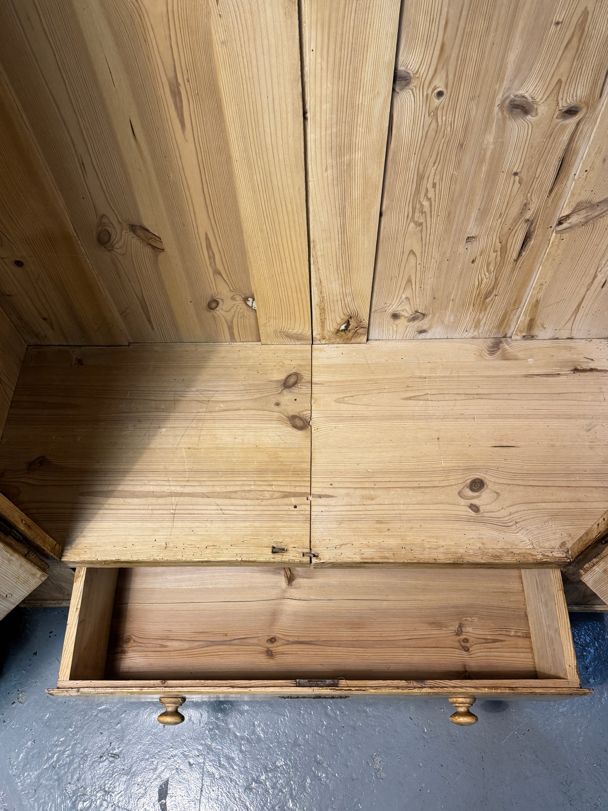 Interior base of antique pine wardrobe with wide floorboards and open full-width lower drawer