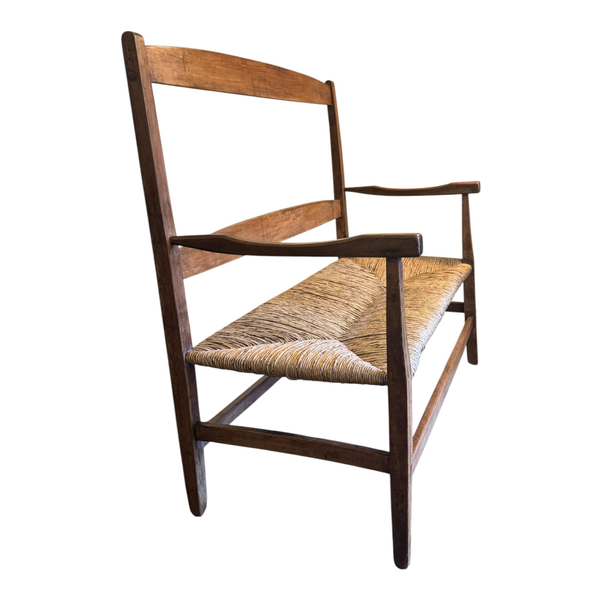 Side view of English Arts & Crafts walnut settee showing low rush seat, shaped arm and traditional frame construction