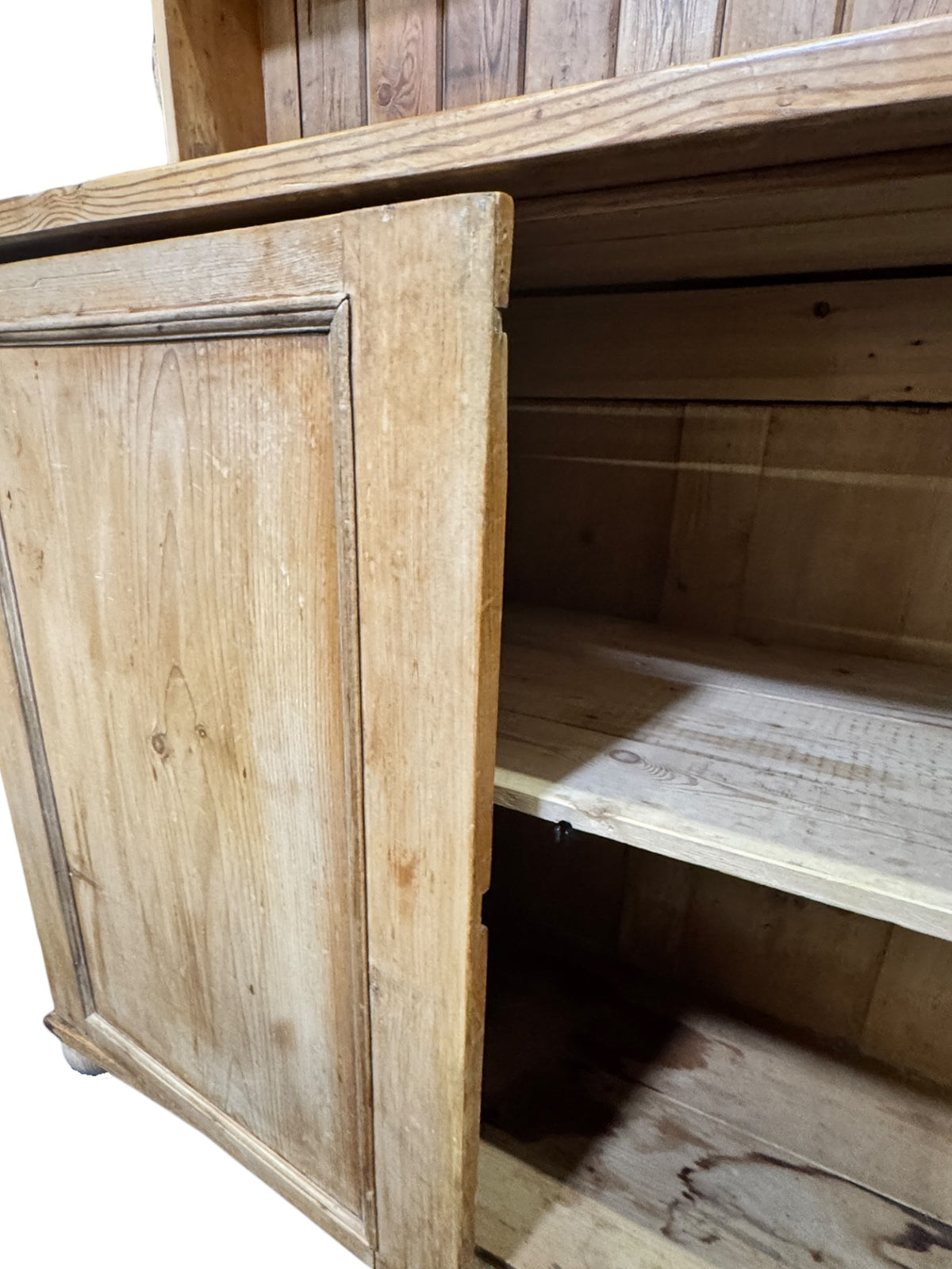Close-up of the panelled cupboard door on an antique pine kitchen dresser showing aged pine grain and patina.