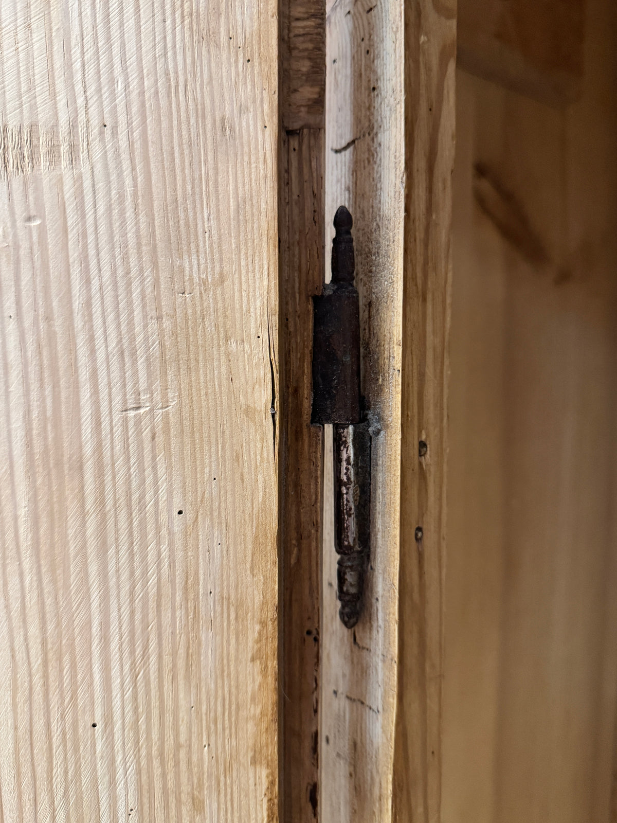Close-up of decorative iron hinge on an antique Victorian pine wardrobe door