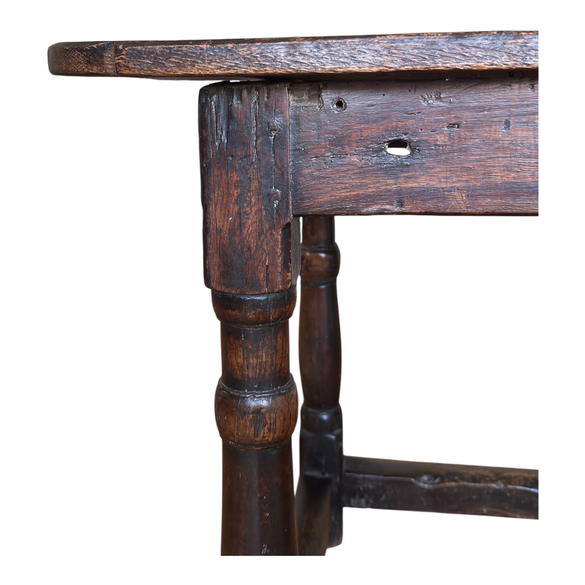 Close-up of the antique oak table showing the broad frieze, turned leg and traditional pegged joinery with deep aged patina.