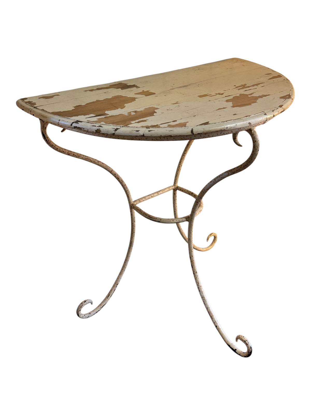 Angled view of vintage wrought iron demi-lune console table with cream painted frame and distressed pine top.