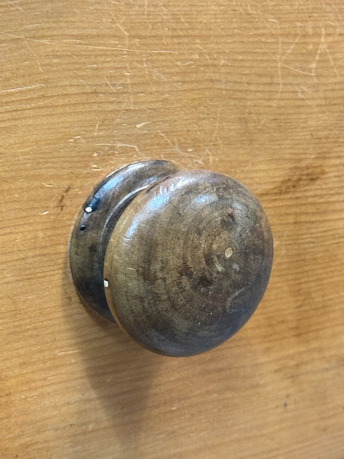 Close-up of aged turned wooden drawer knob on 19th century Victorian pine chest of drawers.