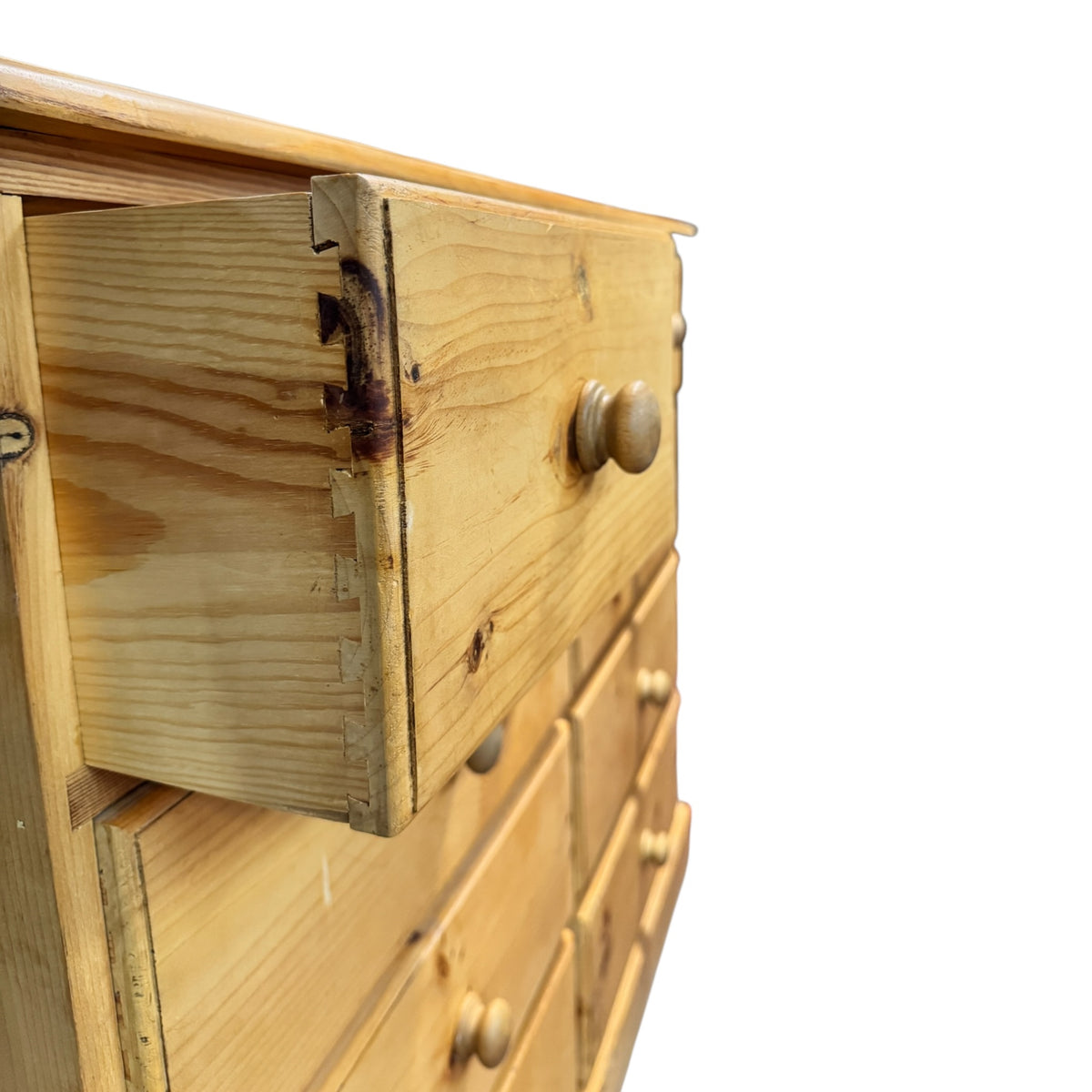 Close-up detail of a vintage pine drawer with dovetail joints, turned wooden knob and visible natural timber grain.