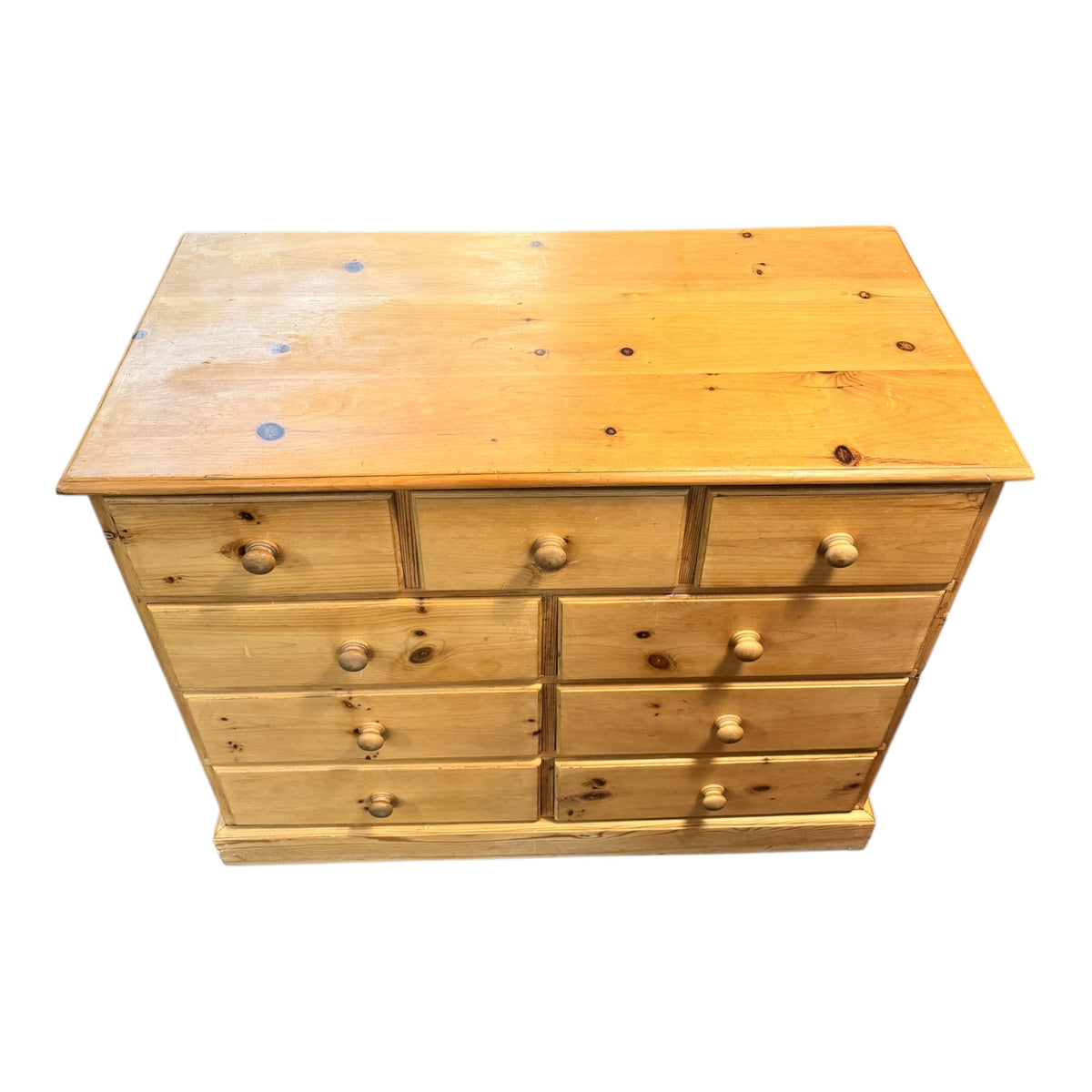 Elevated view of a vintage pine nine drawer chest of drawers showing the solid pine top, drawer arrangement and natural grain.