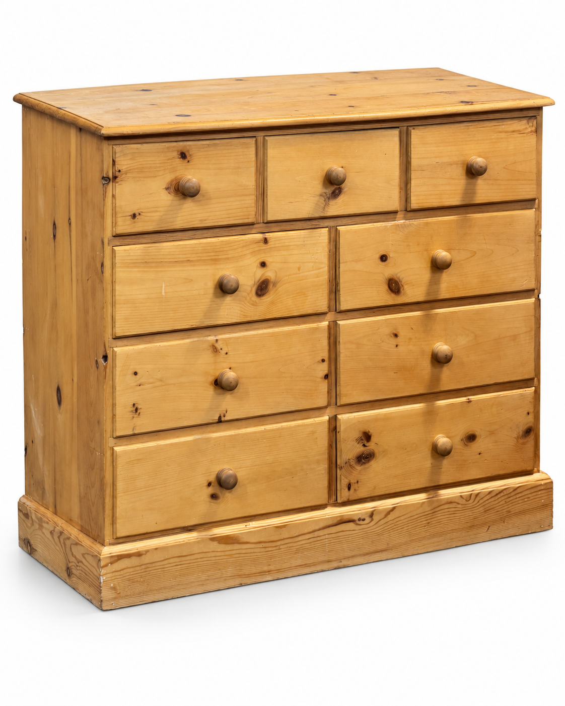 Three-quarter view of a vintage pine nine drawer chest of drawers showing the solid pine top, side panel and turned wooden handles.